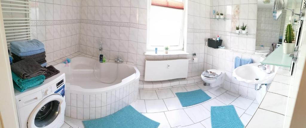 y baño con bañera, lavabo y lavadora. en Schöne Große Wohnung, Terrasse, Kamin, Parkplatz, 2 Schlafzimmer en Greifswald