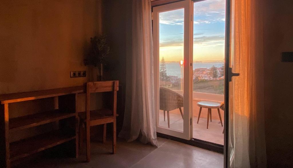 een kamer met een glazen deur naar een balkon bij Azenhas do Mar Valley House in Sintra