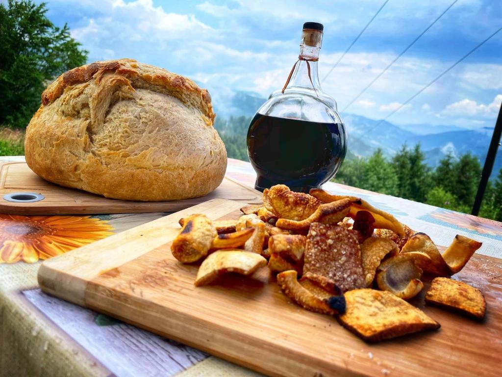 una tabla de cortar con una barra de pan y una botella de vino en Pensiunea Agroturistica Acvila Apusenilor, en Vadu Moţilor