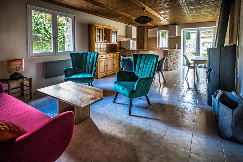 een woonkamer met een bank, stoelen en een tafel bij Gîte Broussas Beach lac de Vassivière in Faux-la-Montagne