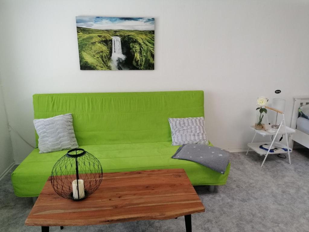 un sofá verde en una sala de estar con mesa en Ferienhaus Elwetritsche in Landau/Pfalz, en Landau in der Pfalz