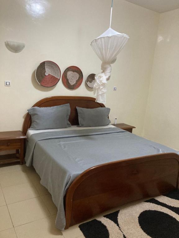 1 dormitorio con 1 cama grande y cabecero de madera en Villa chez Julien, en Rufisque