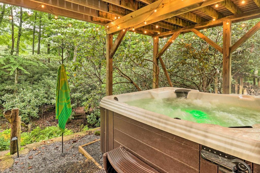 bañera de hidromasaje en el bosque con sombrilla en Tree-Lined Cruso Cabin with Game Room and Mtn Views!, en Canton