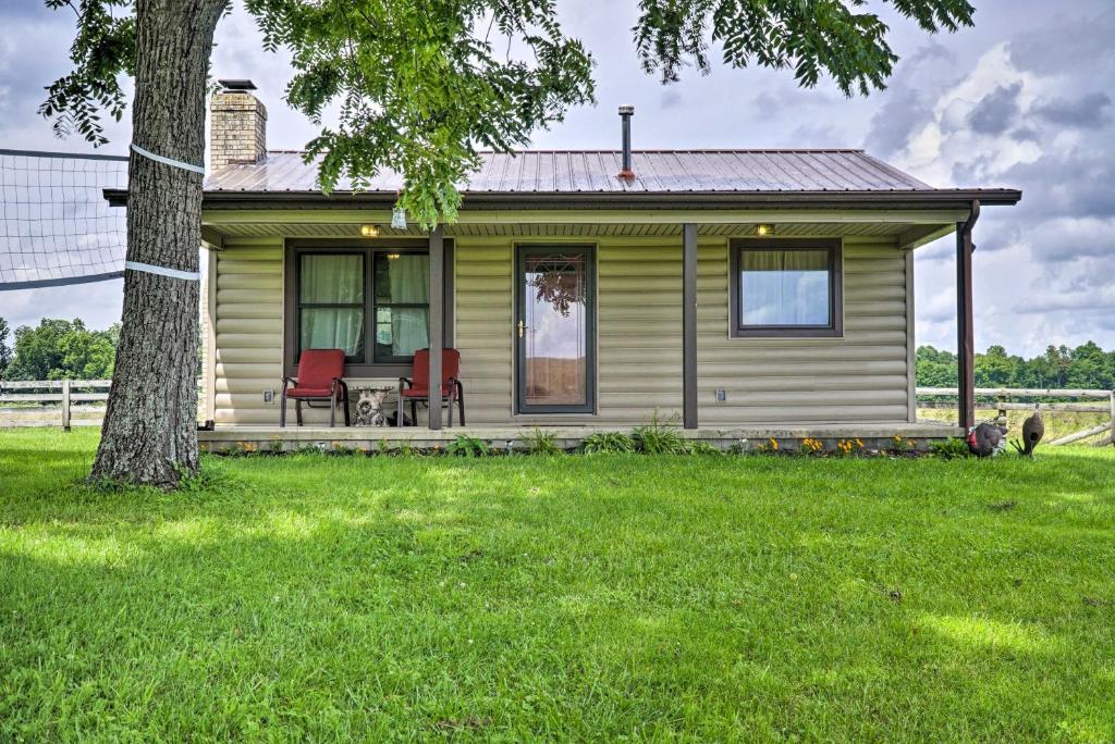 a small yellow house with red chairs in the yard at McArthur Cabin Peaceful Getaway on Farm! in Stella