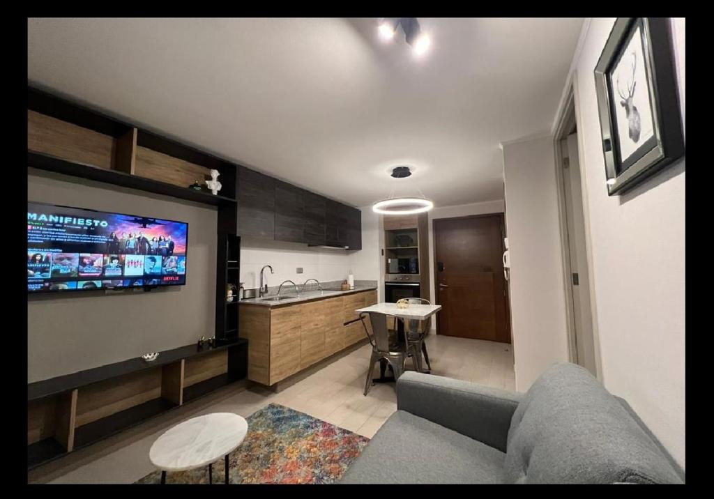 ein Wohnzimmer mit einem Sofa und einem TV an der Wand in der Unterkunft Perfecto departamento 1dorm/1baño in Concepción