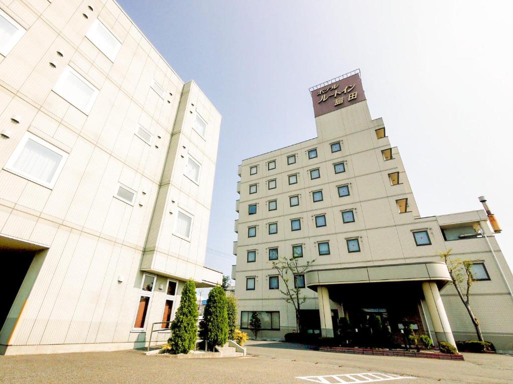 un grande edificio bianco con un orologio sopra di Hotel Route-Inn Shimada Yoshida Inter a Shimada