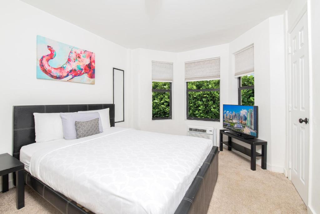 a white bedroom with a bed and a tv at Apartments in the Heart of Miami - Port of Miami / Miami Airport in Miami