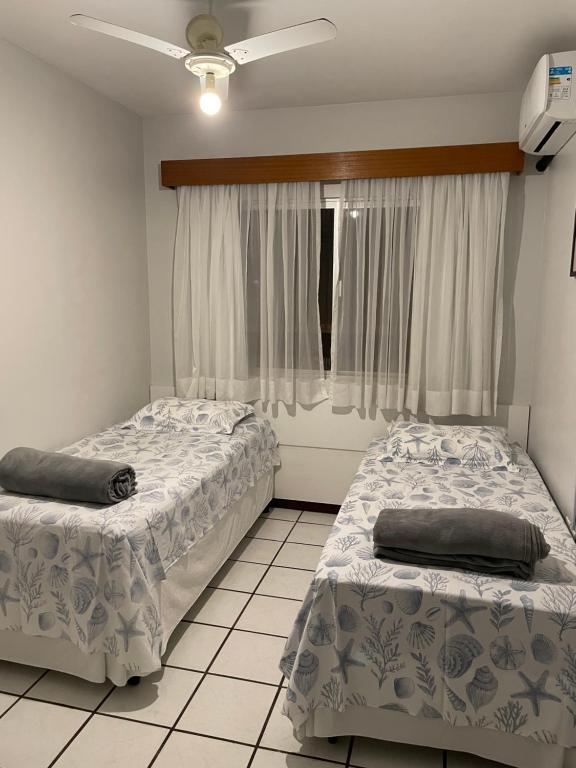 two beds in a room with a window at Apartamento amplo e completo no centro Balneário Camboriú in Balneário Camboriú
