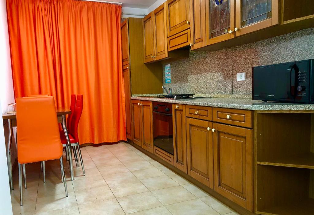 a kitchen with wooden cabinets and an orange curtain at URBAN Apartment - Slatina City Centre in Slatina