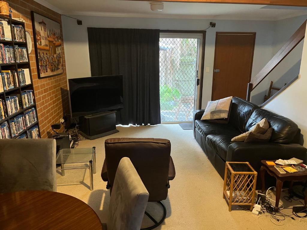 a living room with a black leather couch and a television at Hill Haven in Brisbane