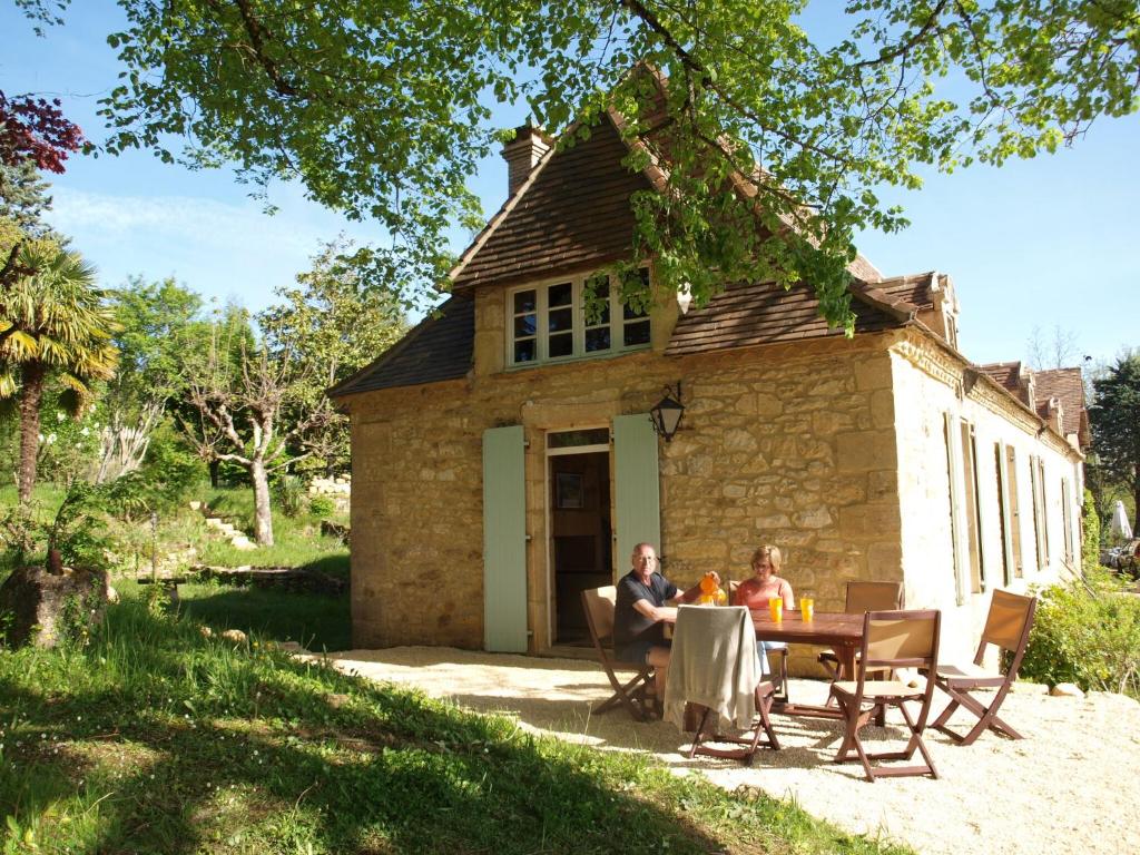 deux personnes assises à une table devant un bâtiment dans l'établissement Cozy Cottage in Aquitaine with Private Swimming Pool, à Peyzac-le-Moustier