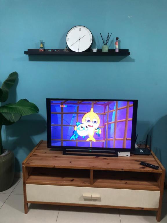 - une télévision sur une table avec une horloge au mur dans l'établissement Qmar Melaka Homestay, à Kampong Kerubong
