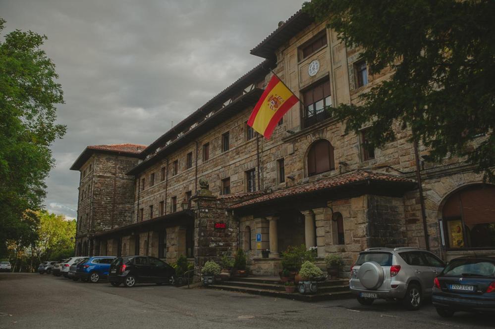 un gran edificio de piedra con una bandera delante de él en Balneario de Corconte, en Cabañas de Virtus