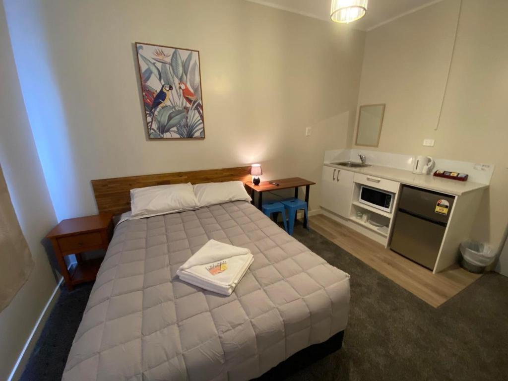 1 dormitorio con 1 cama y cocina pequeña en Airport Westney Lodge, en Auckland