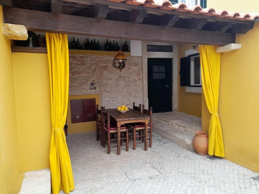 a patio with yellow curtains and a table and chairs at Casinha da Pena - Tomar (Pedreira) in Tomar