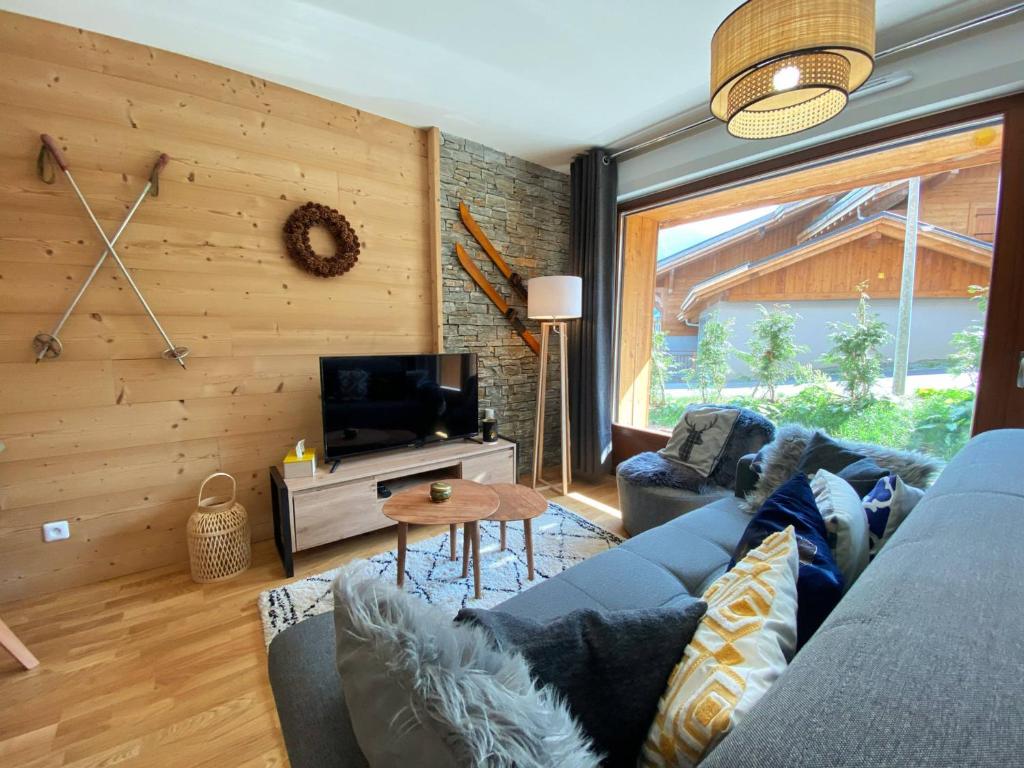 un salon avec un canapé bleu et une télévision dans l'établissement Charmant T3 Neuf, Skibus Gratuit, Terrasse, 2 Places Privées, WIFI - Samoëns - FR-1-624-122, à Samoëns