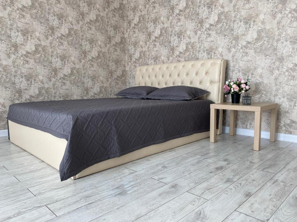 - une chambre avec un lit et une table fleurie dans l'établissement Однокомнатная студия, центр, à Kostanay