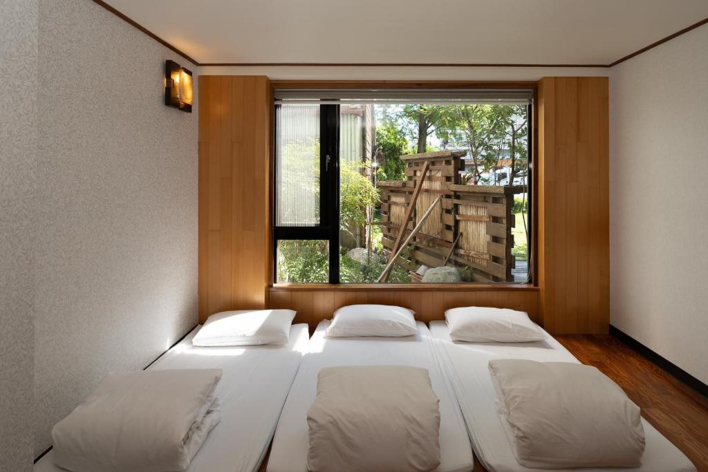 a room with three beds in front of a window at 檜木居民宿 - 立案證號 一六三 - 一六八 - 一七零 in Ji&#39;an
