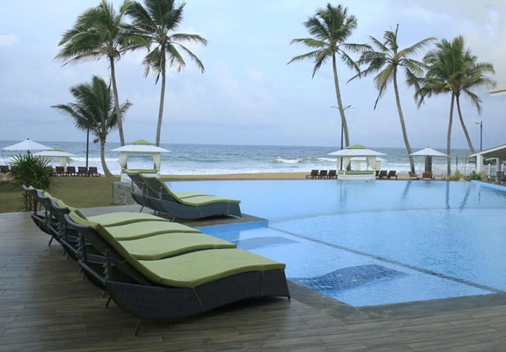 a swimming pool next to the beach with palm trees at Avenra Beach Hikkaduwa in Hikkaduwa