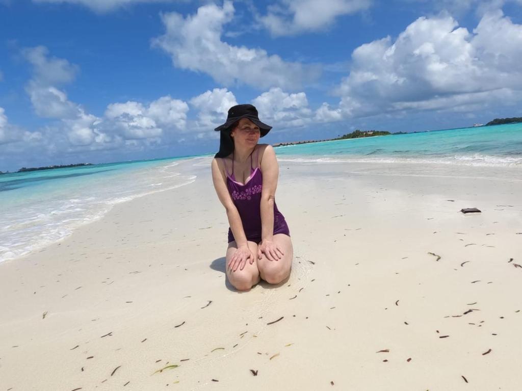 a young woman sitting on the beach at La Isla Tropica in Guraidhoo
