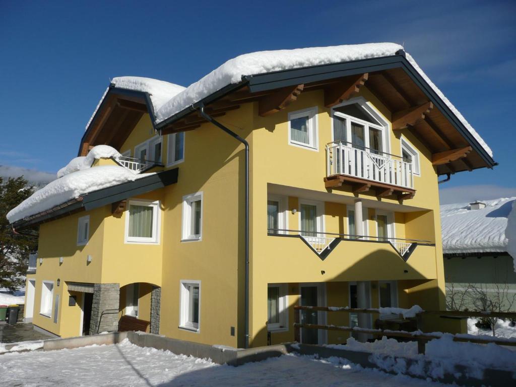 a yellow building with snow on the roof at Appartement Königslehen in Radstadt