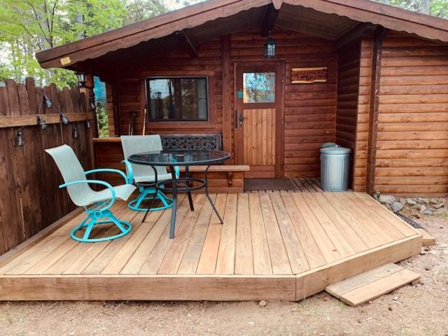 een houten terras met een tafel en stoelen voor een hut bij Lakeshore Lily Pad in Hayward