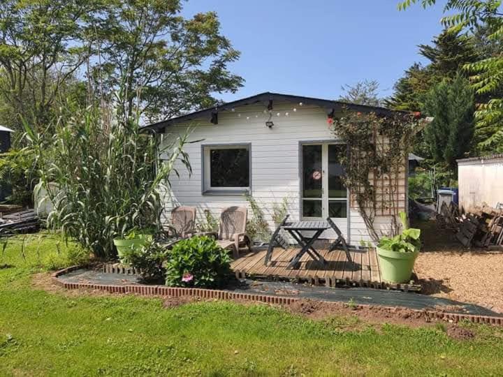 une petite maison blanche avec une table et des chaises dans l'établissement jolie cocon au coeur de la nature, à Durtal