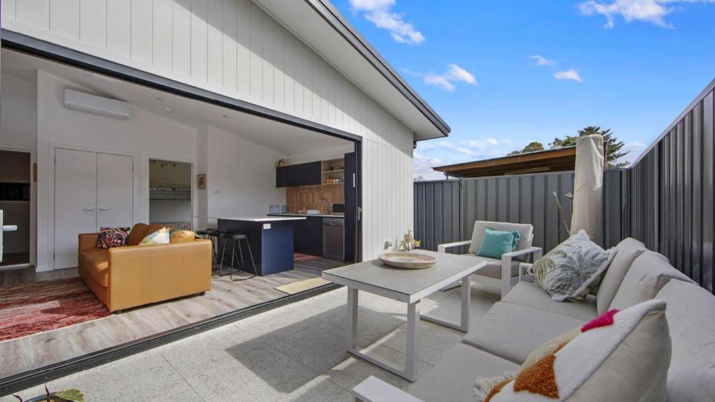 a patio with a white couch and a table at Summer Vibes Cabin Wifi in Ettalong Beach