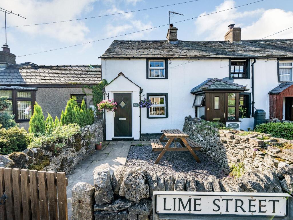 a white cottage with a picnic table in front of it at Kidsty Cottage in Penrith