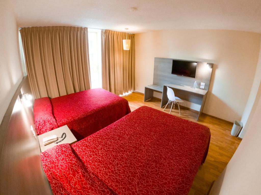 a hotel room with two red beds and a desk at Hotel Del Angel Reforma in Mexico City