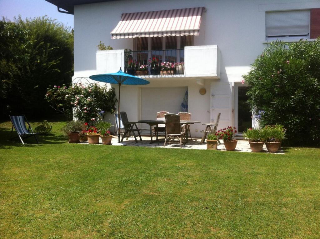 a patio with a table and an umbrella in a yard at T1 ou T2 dans villa avec jardin proche Biarritz in Anglet