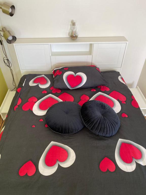ein Bett mit zwei Kissen und roten Blumen darauf in der Unterkunft Mājīgs studio apartaments jūras pilsētā in Ventspils