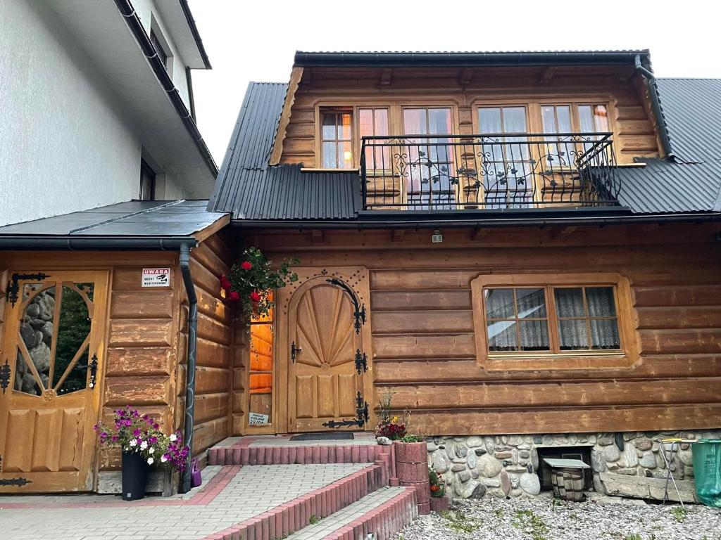 uma casa de madeira com uma varanda em cima em Góralski Apartament em Witów