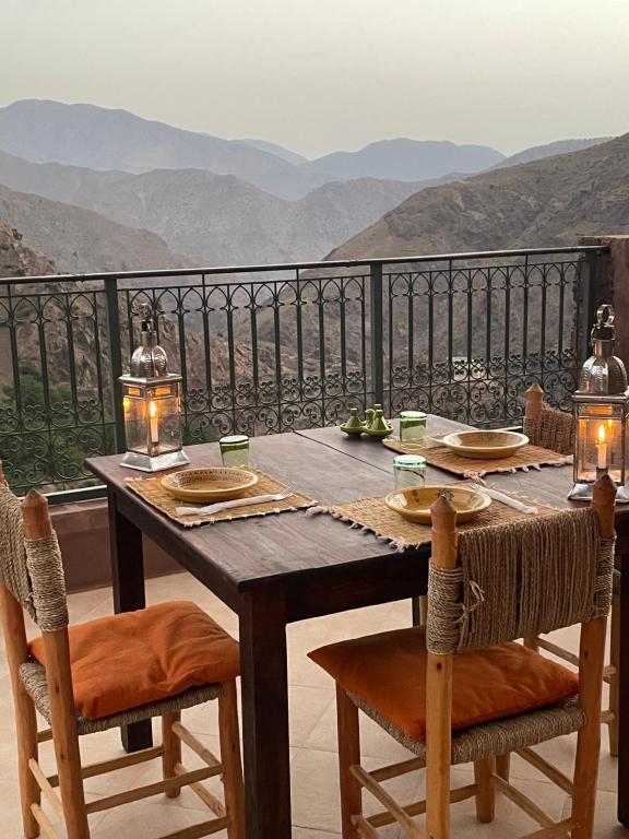 una mesa de madera y sillas con vistas a las montañas en Issouganes N Toubkal Maison d hôtes en Oussertek