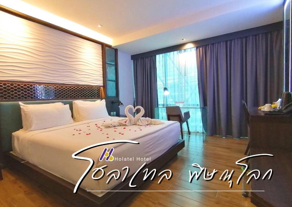 a hotel room with a bed with a bow on it at Holatel in Phitsanulok