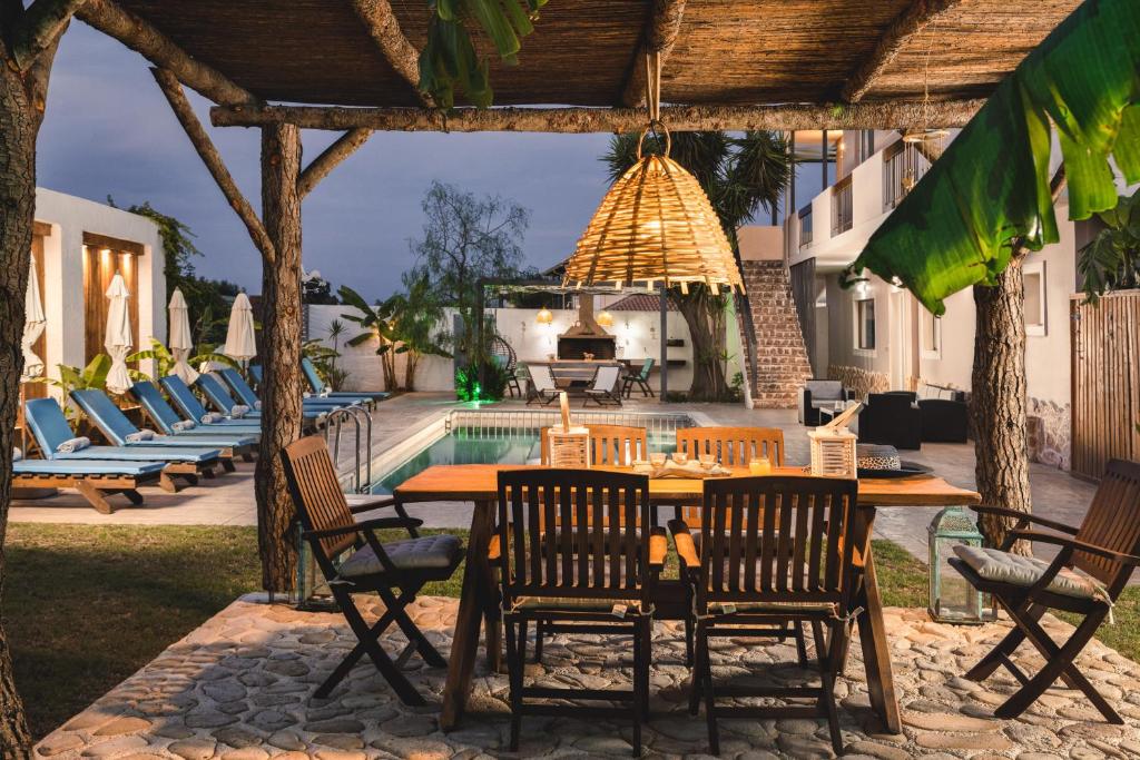 een patio met een tafel en stoelen en een zwembad bij Bruma Luxury Residence in Mouzákion