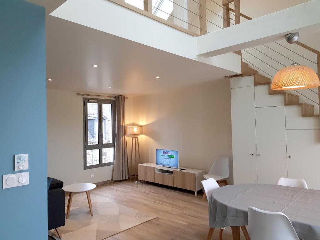 a living room with a dining room table and a television at COTE CIEL - CANCALE - GITE STANDING - PROCHE CENTRE ET PORT in Cancale