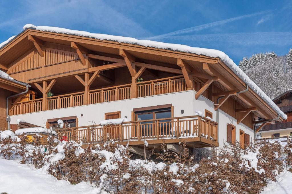 une cabane en rondins avec une terrasse dans la neige dans l'établissement Apartment La Colombe, aux Gets