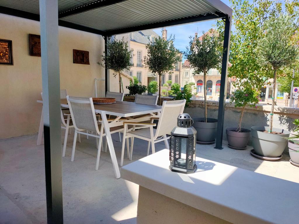 eine Terrasse mit einem Tisch, weißen Stühlen und einem Tisch in der Unterkunft la buffonnière in Montbard