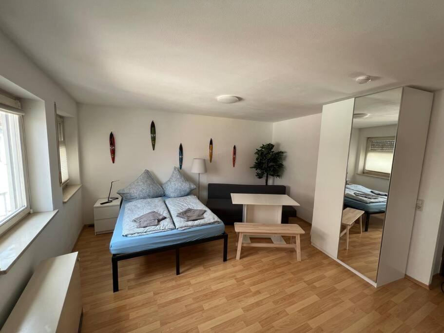 Cette chambre comprend un lit, une table et un miroir. dans l'établissement kleines Apartment im Zentrum von Würzburg, à Wurtzbourg