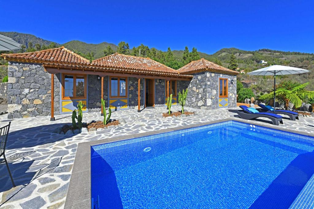 a villa with a swimming pool in front of a house at Casa El Vendaval in Tijarafe