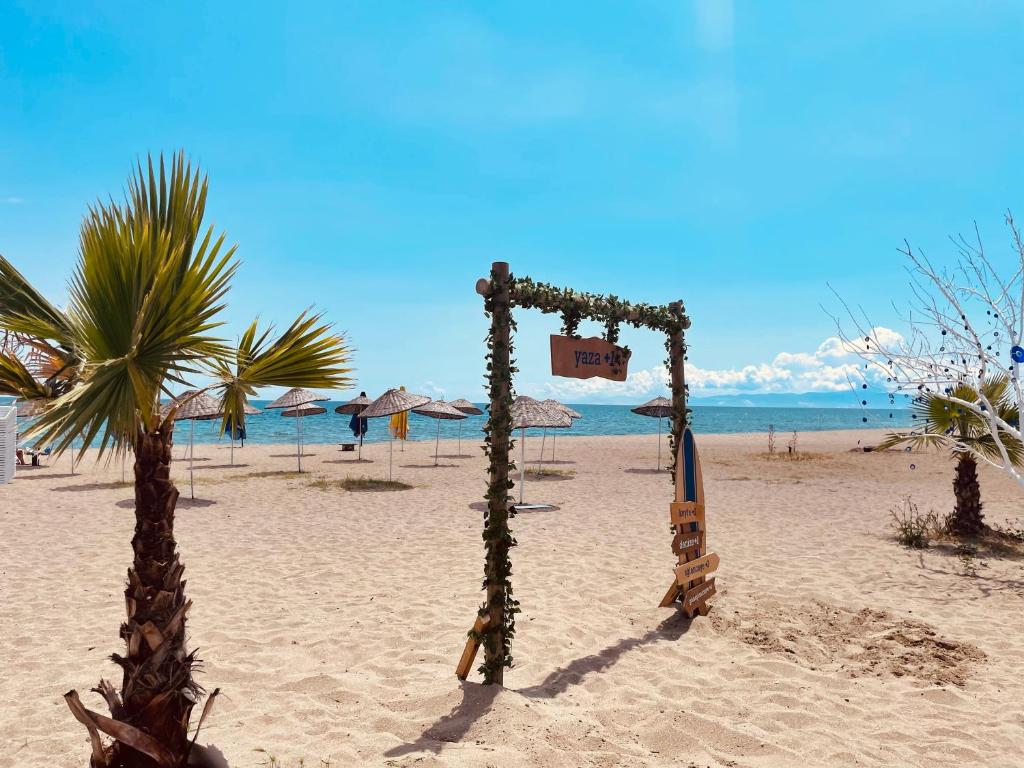 a beach with two palm trees and a sign on it at NOVA PORT Boutique Hotel in Tekirdağ