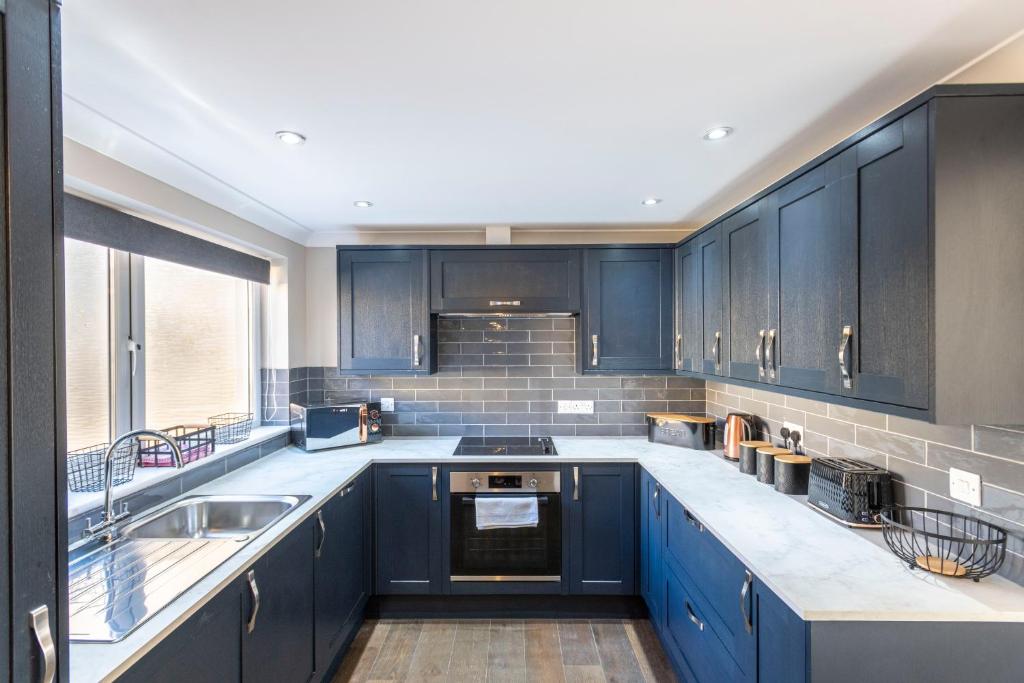a kitchen with blue cabinets and a sink at Newly renovated 2 bed house with large garden. in Phillack