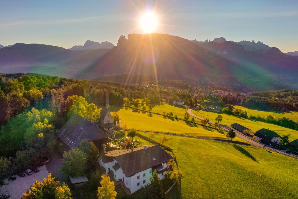 une vue aérienne sur une maison dans un champ avec coucher de soleil dans l'établissement Hotel Ansitz Kematen ***S, à Collalbo