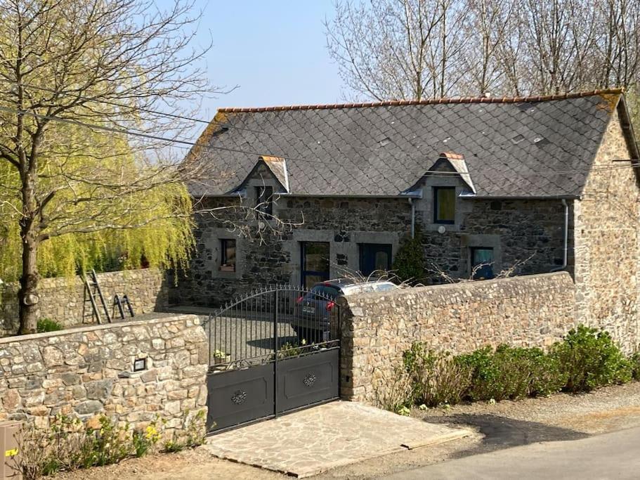 a stone house with a gate and a stone wall at La petite maison terre mer in Plélo