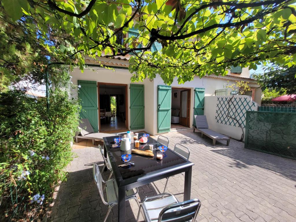 a patio with a table and chairs in a yard at Villa 78 m2 - Au Chant des Cigalous in Six-Fours-les-Plages