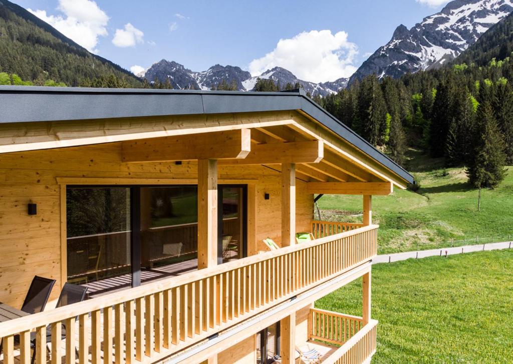 um chalé de madeira com um deque e montanhas ao fundo em Ferienwohnung Schwendle Egg em Mittelberg