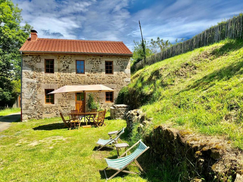 ein Steinhaus mit einem Tisch und Stühlen auf einem Hügel in der Unterkunft La petite Maison du Bonheur & Jacuzzi 