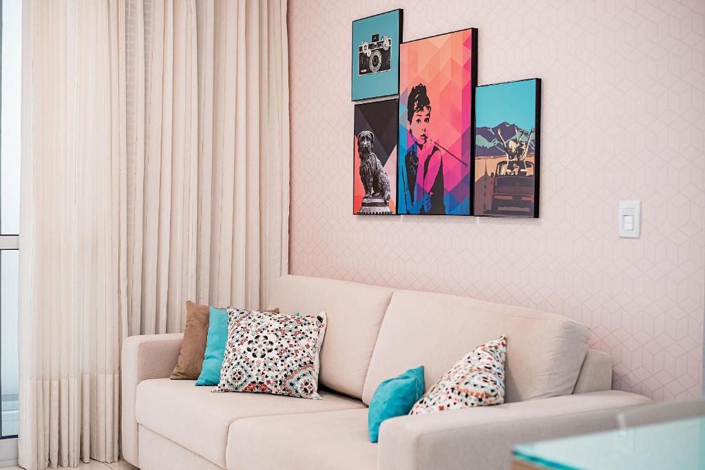 ein Wohnzimmer mit einer weißen Couch und vier Bildern an der Wand in der Unterkunft Studio c Localização Exclusiva em Jardim da Penha in Vitória