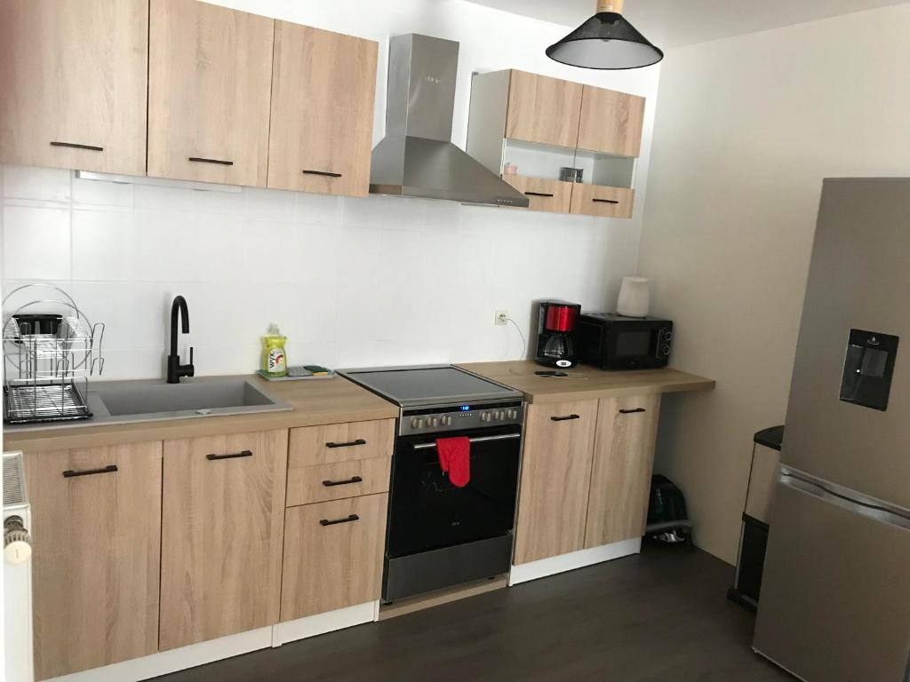 a kitchen with wooden cabinets and a black stove top oven at Au Faubourg in Saint-Claude